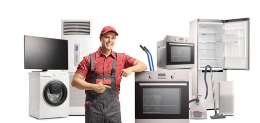 Repairman leaning and pointing to an electric oven with other home appliances in the back