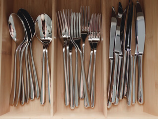 steel gray stylish modern spoons, forks, knives, service, kitchen set on the shelf of the store,...