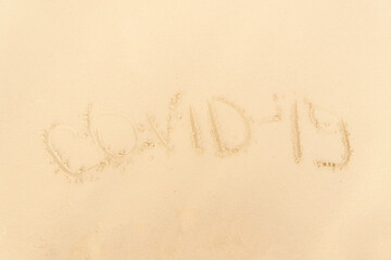 Travel and tourism concept, novel coronavirus 2019-nCoV pandemic alert. The inscription covid-19 is made on the sandy beach.