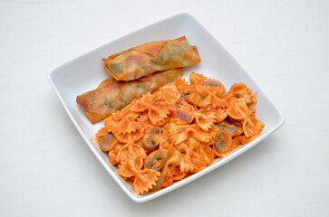 A meal of Toasted Egg-rolls and Bowtie Pasta with Caramelized Red Onions and Mushrooms (in Red Tomato Sauce).