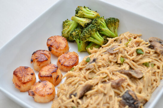 A meal of Saut&eacute;ed Scallops, Broccoli, and whole-wheat spaghetti with mini portobello mushrooms and scallion.