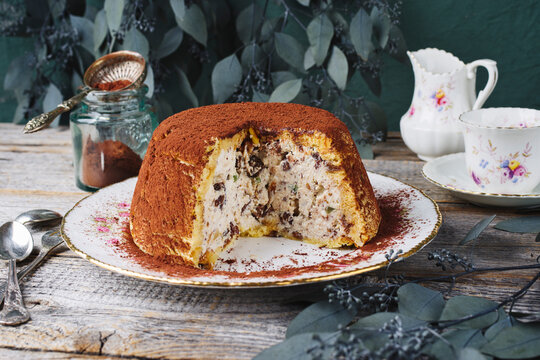 Traditional Italian Panettone cake stuffed with ricotta pudding, glanced fruits and raisins served as close-up on a classic design plate