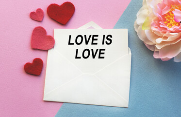 An open envelope with the text LOVE IS LOVE, on a pink and blue background with a decor of felt hearts and a flower. Flat lay, top view. LGBT concept.