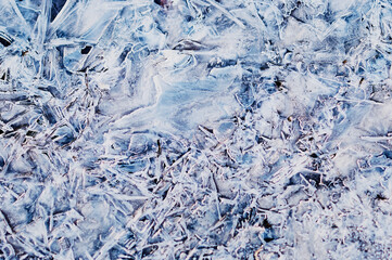 Thin ice in the morning on a rocky beach. Sunrise. Night frosts. Close view. Natural abstract texture. Changeable weather in spring.