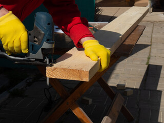 a man saws a board with an electric jigsaw close-up .hand electric saw ,the concept of working with...