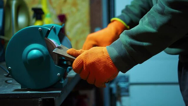 man sharpening an ax blade on a grinder