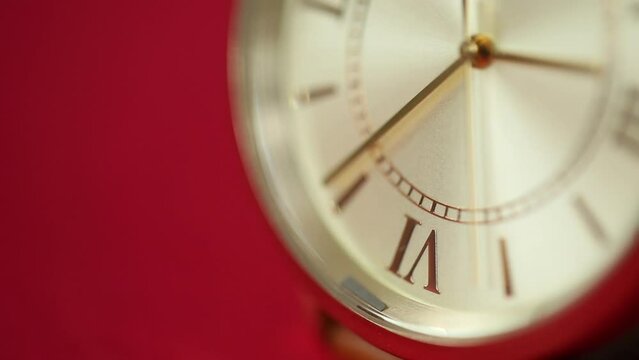 gold metallic second on  clock face. Red background for copy space. macro watch.