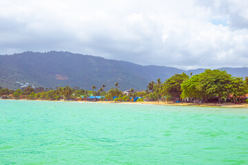 Tropical sea coast with houses and palm trees on the shore. Travel and tourism