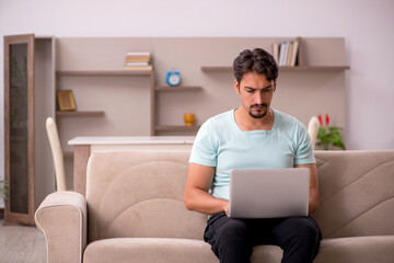 Young man sitting on the sofa with computer at home