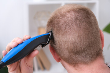 A man cuts his hair with a clipper. Cutting a short hairstyle at home. Close-up.