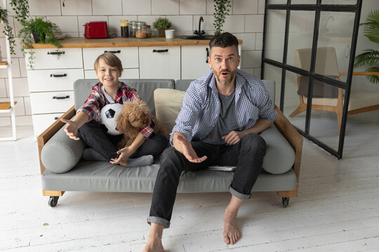 Handsome young father and his teenager son spending quality time together, watching sport game, football, hockey. Family time, having fun, enjoy. Fatherhood, parenting concept. Two generations