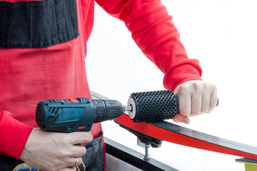 Ski service. In the hands of the serviceman a drill with a brush for preparing cross-country skis