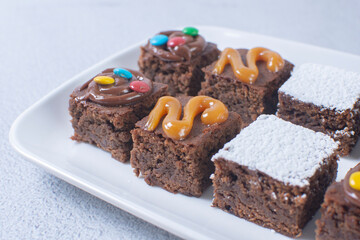 Variety of brownies with chocolate, arequipe and powdered sugar on a gray background
