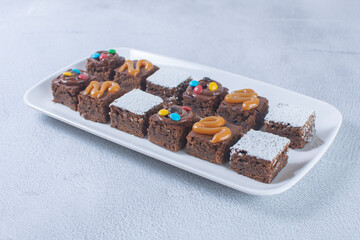 Variety of brownies with chocolate, arequipe and powdered sugar on a gray background