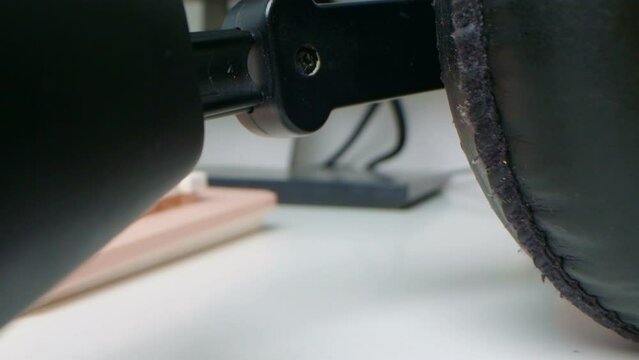 detailed extreme close-up of black wired headphones and pink computer keyboard on white table