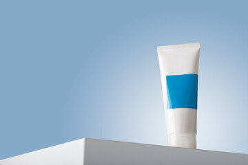 White care cosmetics tube with blue blank label mockup, face skin cream or mineral tooth paste container template on white table podium