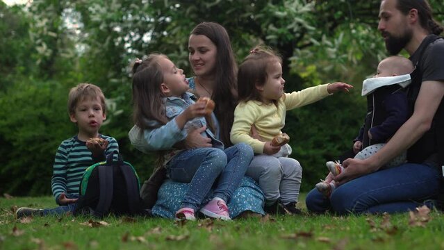 Happy family mother Father Three four Baby little siblings kids have fun blowing bubbles enjoying summer holidays in garden park. Smiling parents children spending leisure time together evening sunset