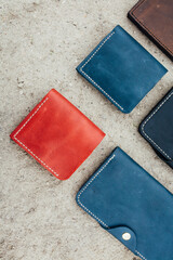 wallets of different colors of leather lie on the sand folded in a collage