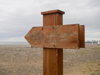Wooden pointer on the beach. Mockup in nature. Recreation and tourism.
