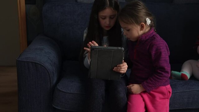 authentic 3 little preschool toddler minor children kids siblings watch cartoon playing games online chating on smartphone device laptop tablet together at home indoors. Family, childhood, friendship