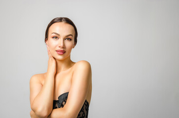 Fototapeta premium Beautiful young brunette woman with perfect skin at gray background. Skin and facial care. Cosmetology and beauty