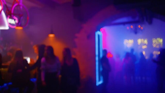 Blurry: Many happy people partying and in a nightclub and walking around with glasses of aclohol
