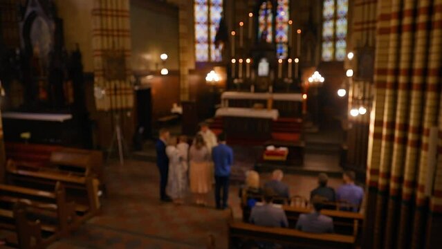 Catholic family baptising their baby in a church - Defocused background footage