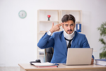 Young neck injured male employee sitting in the office