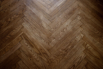 Classic wooden oak parquet in the form of a dark brown Christmas tree. Brown seamless parquet floor with a pattern of spruce from narrow boards