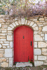 Fototapeta na wymiar Red wooden door of traditional stone house. Architectural elements.
