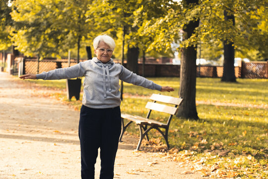 Elderly pensioner European gray-haired lady takes care of her health by exercising in the open air. Vitality and strength among seniors. High quality photo