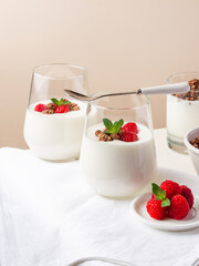 yogurt with raspberries and granola in glasses on a white table