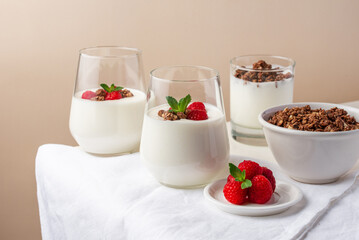 yogurt with raspberries and granola in glasses on a white table