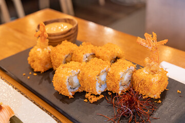 Ebi Tempura Maki (Fried Prawn or shrimp Sushi roll) on slate. Japanese traditional fusion food style, restaurant menu. Close up photo with selective focus.