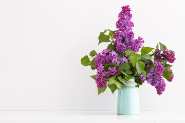 Charming bouquet of blooming lilac in vase on grey