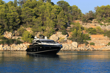 Luxury black motor yacht moored near the island