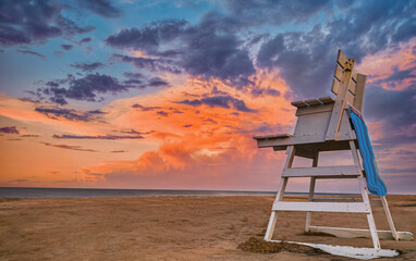 sunset on beach with lifeguard chair room for text - obrazy, fototapety, plakaty