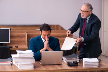 Old male employer and young male assistant in bullying concept