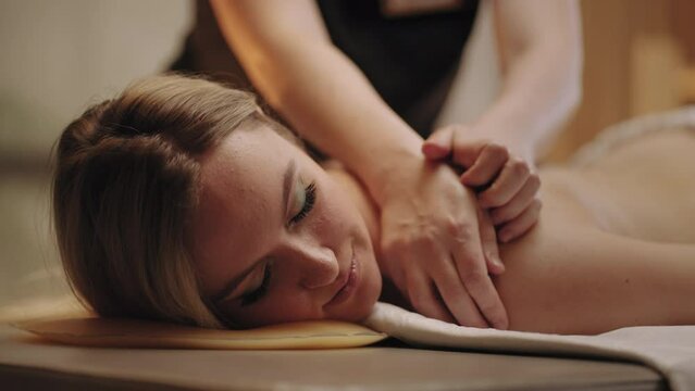 beauty and relax day in spa salon, young woman is enjoying professional massage, physician is massaging back