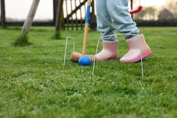 Girl playing croquet on green grass outdoors, closeup