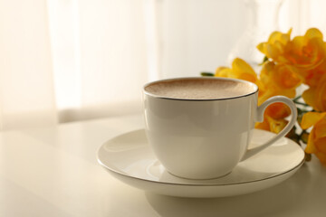 Delicious morning coffee and flowers on white table indoors, space for text