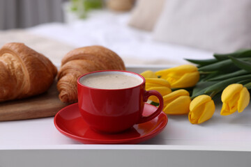 Morning coffee, croissants and flowers on white wooden tray indoors