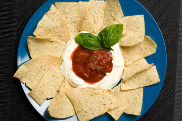 Plate of nachos with sour cream and salsa
