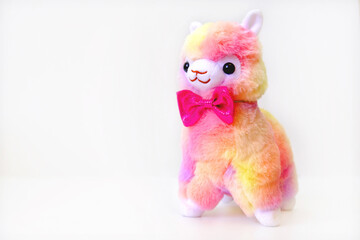 Fluffy funny toy llama, soft stuffed toy on white background, alpaca doll. Nersery bedroom decor