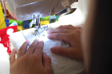 ミシンで縫う女の子の手のアップ - obrazy, fototapety, plakaty