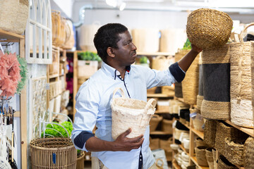 Focused African American looking for decorative wicker basket for storing household goods at store....