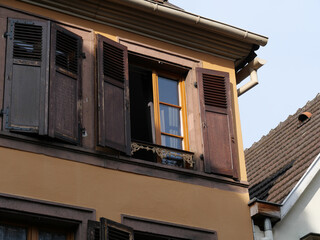 Fototapeta na wymiar Geöffnetes Fenster mit brauenen Fensterläden am Eck eines alten Hauses im Elsass