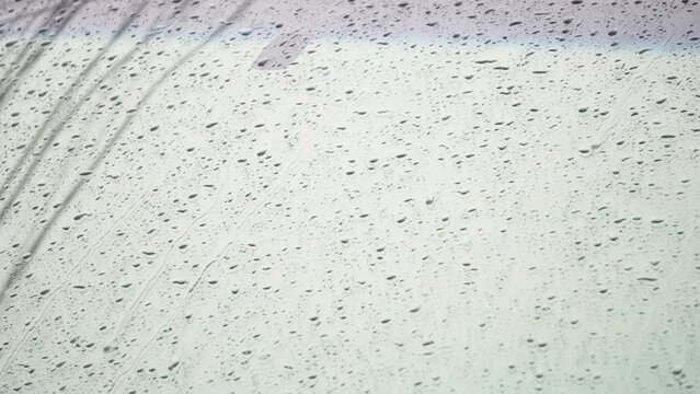 Slow motion and close up of a carglass while it&rsquo;s raining