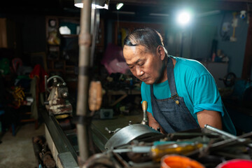 Fototapeta na wymiar The senior mechanic has a serious expression, in operation, and controls the lathe, closely and very carefully.