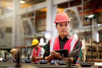Factory worker with helmet using digital tablet to measure the product from production line quality with standard measurement at heavy metal manufacturing industrial, specialist engineer.